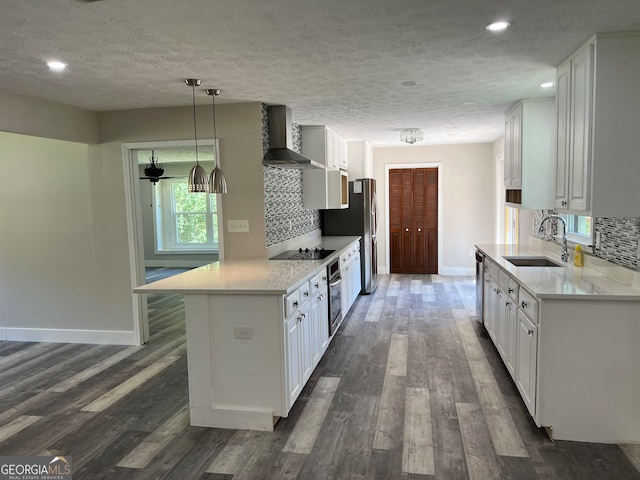 kitchen featuring sink, wall chimney exhaust hood, dark wood-type flooring, white cabinetry, and decorative backsplash