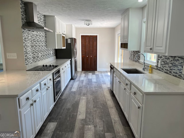 kitchen featuring sink, dark wood-type flooring, wall chimney range hood, white cabinetry, and stainless steel appliances