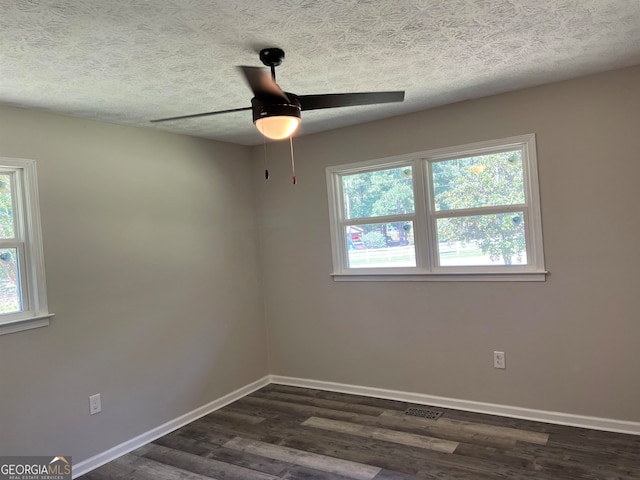 empty room featuring ceiling fan, a textured ceiling, dark hardwood / wood-style floors, and a healthy amount of sunlight