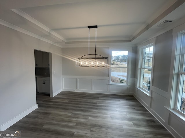 unfurnished dining area with dark hardwood / wood-style floors, a raised ceiling, and a notable chandelier