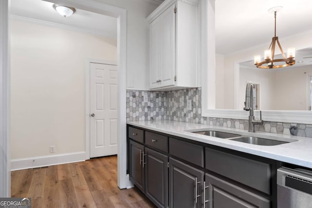 kitchen featuring white cabinets, ornamental molding, hardwood / wood-style floors, a chandelier, and sink