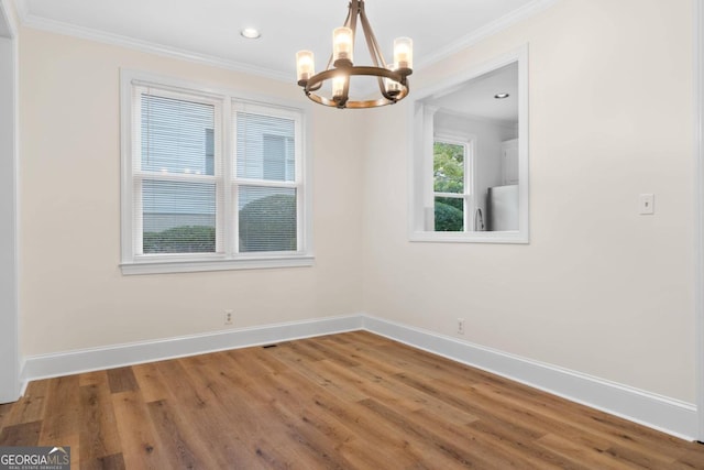 unfurnished dining area featuring an inviting chandelier, crown molding, and hardwood / wood-style floors