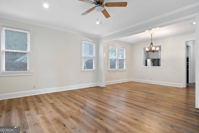 spare room with ceiling fan with notable chandelier, ornamental molding, and wood-type flooring