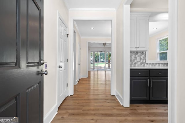 hall with light wood-type flooring, plenty of natural light, and crown molding