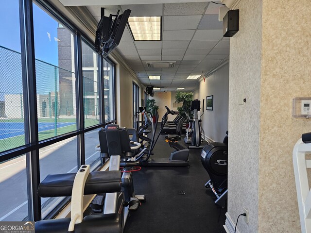 gym with crown molding, expansive windows, and a paneled ceiling