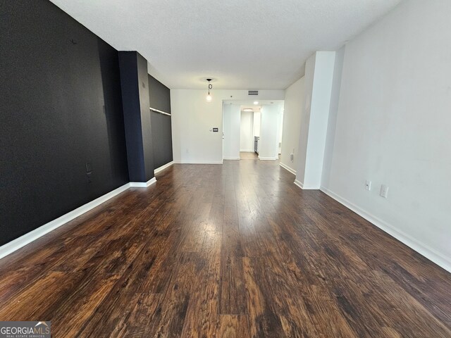 unfurnished living room featuring a textured ceiling and dark wood-type flooring