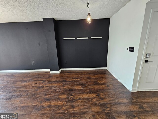 spare room with a textured ceiling and dark hardwood / wood-style flooring