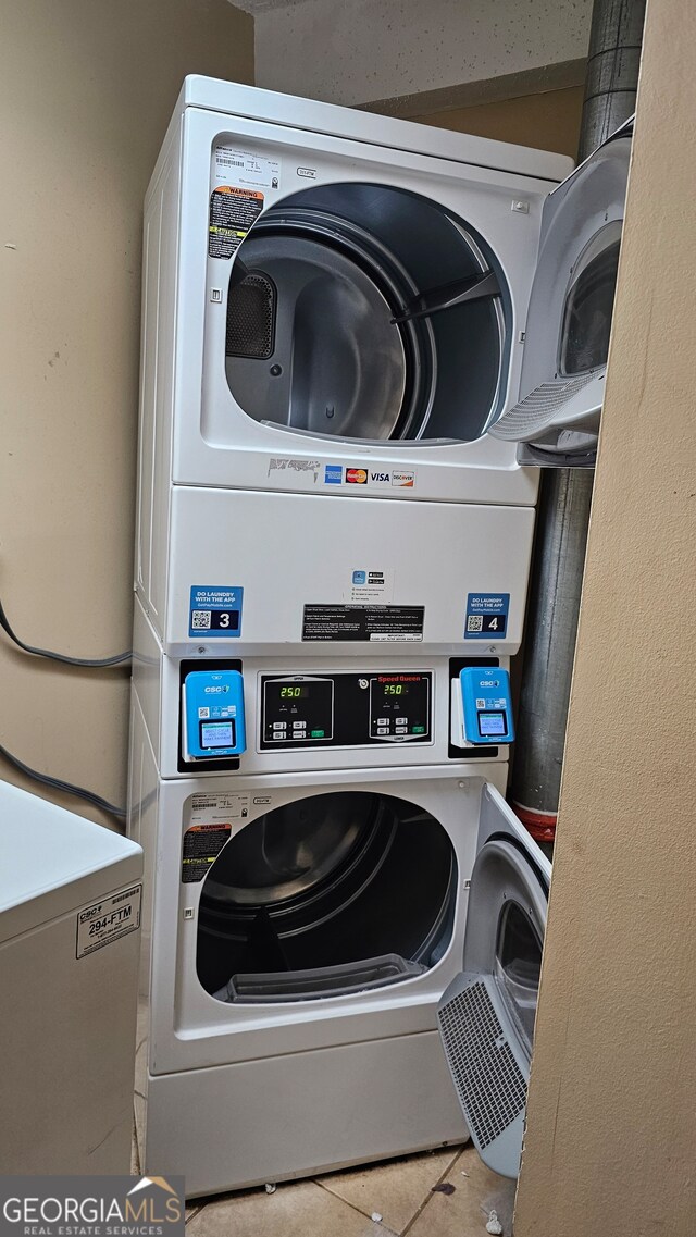 clothes washing area with stacked washing maching and dryer and light tile patterned floors