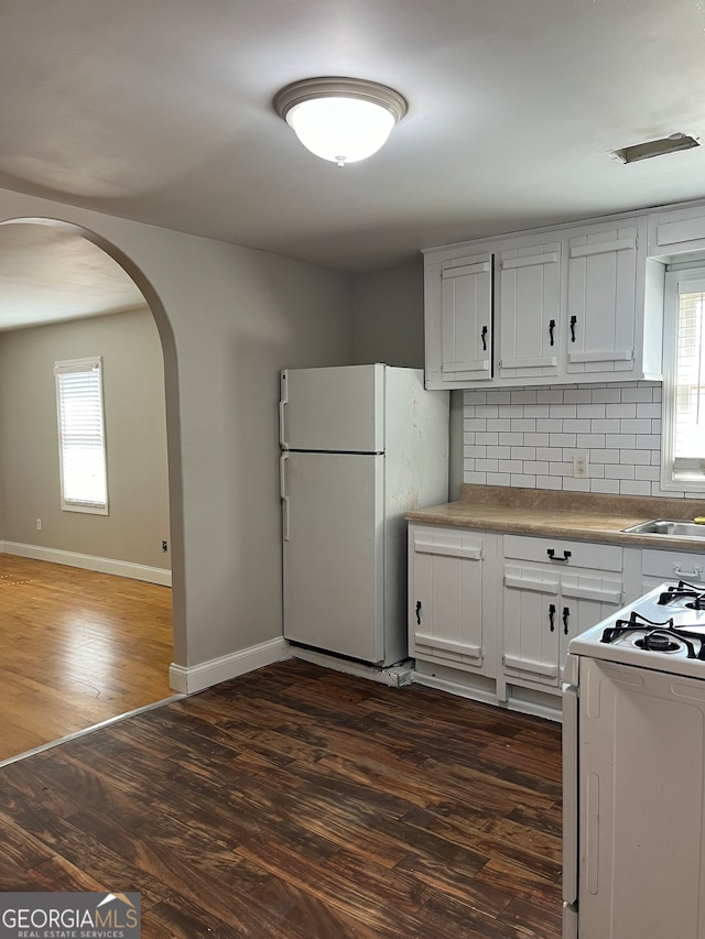 kitchen featuring white appliances, white cabinetry, dark hardwood / wood-style flooring, and tasteful backsplash