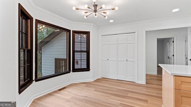 interior space featuring an inviting chandelier, a closet, crown molding, and light hardwood / wood-style flooring