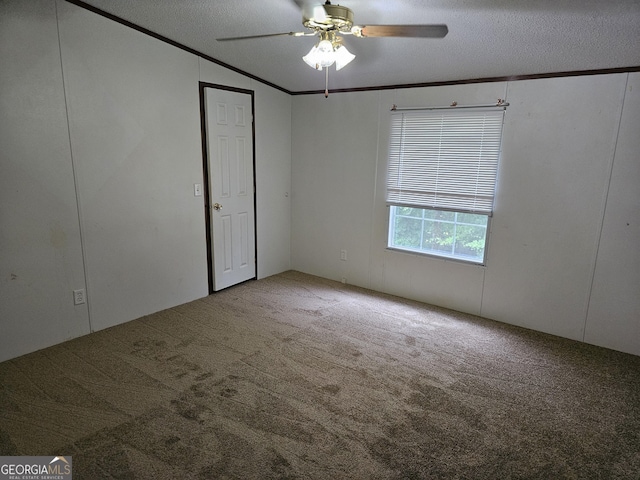 carpeted empty room featuring ceiling fan, crown molding, a textured ceiling, and vaulted ceiling