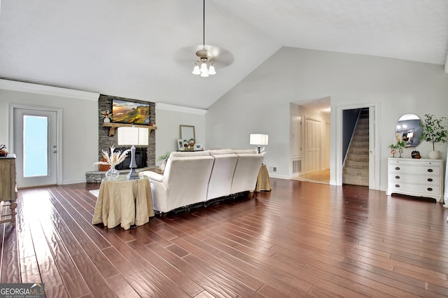 living room with dark wood-type flooring, high vaulted ceiling, a fireplace, ceiling fan, and ornamental molding