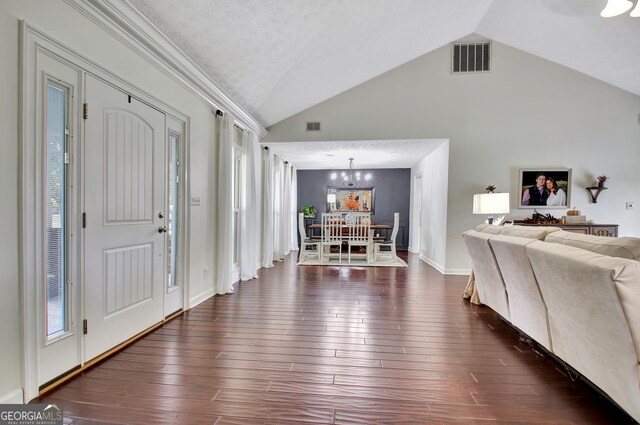 entryway with a textured ceiling, vaulted ceiling, and dark wood-type flooring