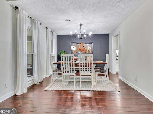 dining area featuring a textured ceiling, dark hardwood / wood-style floors, and a chandelier