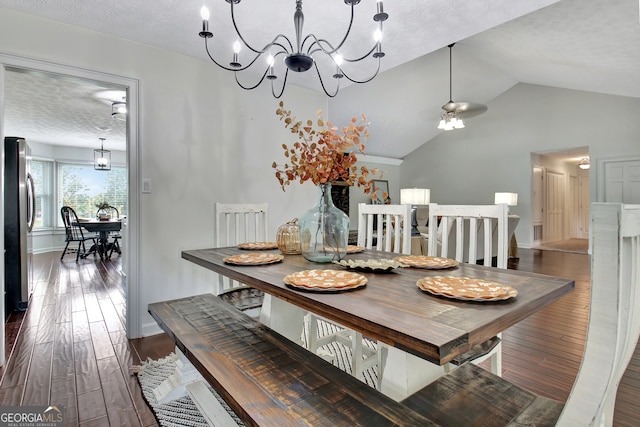 dining area with a textured ceiling, lofted ceiling, dark hardwood / wood-style flooring, and a notable chandelier