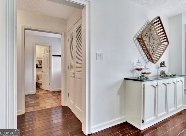 hallway with a textured ceiling and dark hardwood / wood-style flooring