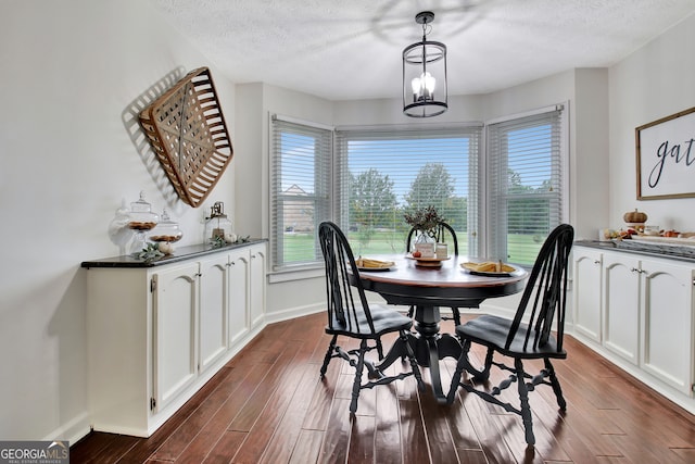 dining space featuring a textured ceiling, dark hardwood / wood-style floors, and a notable chandelier