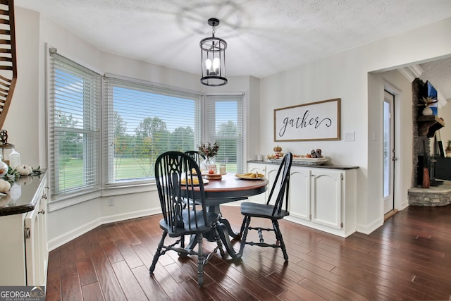 dining space with a wealth of natural light, a textured ceiling, and dark hardwood / wood-style floors