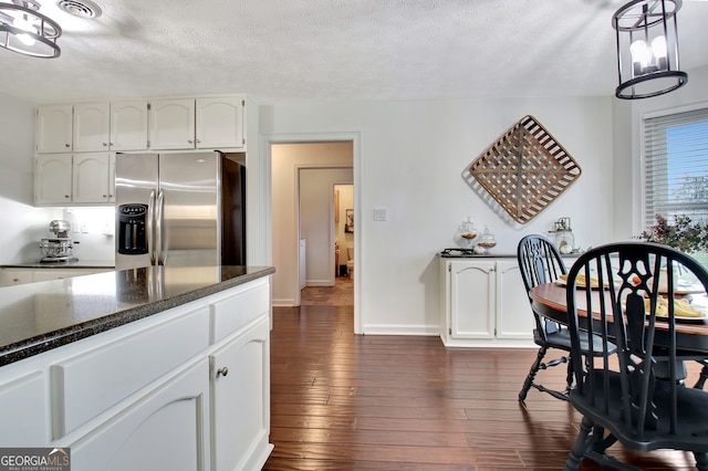 kitchen with a textured ceiling, dark hardwood / wood-style flooring, stainless steel fridge with ice dispenser, and white cabinetry