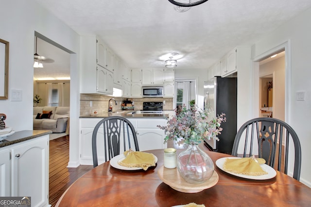 dining room featuring a textured ceiling, sink, and dark wood-type flooring