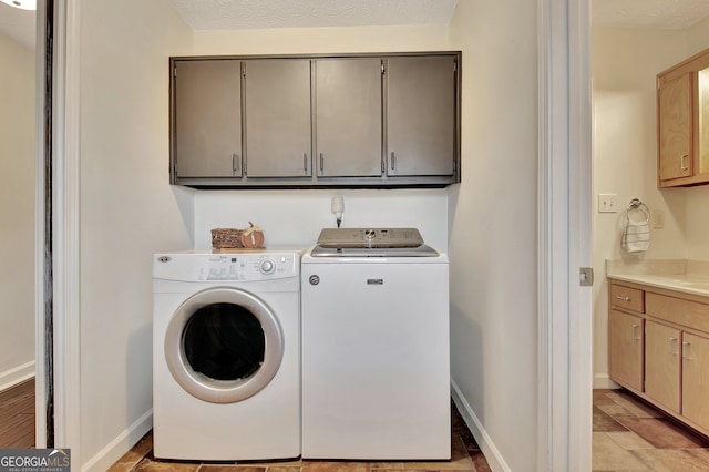 laundry room featuring cabinets, a textured ceiling, and independent washer and dryer