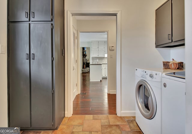 clothes washing area with washer and clothes dryer, cabinets, and light hardwood / wood-style flooring