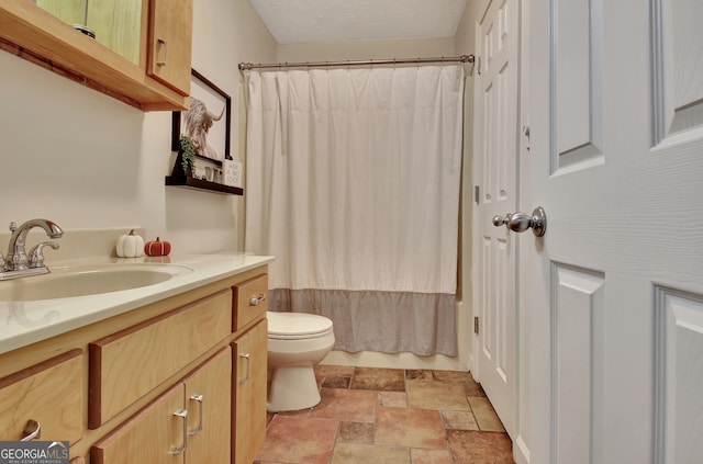 bathroom featuring vanity, toilet, and a textured ceiling