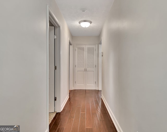 hallway with a textured ceiling and dark hardwood / wood-style floors