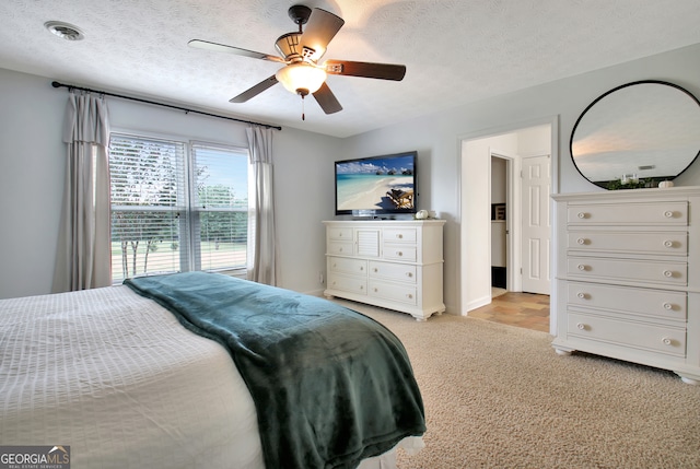 carpeted bedroom featuring ceiling fan and a textured ceiling