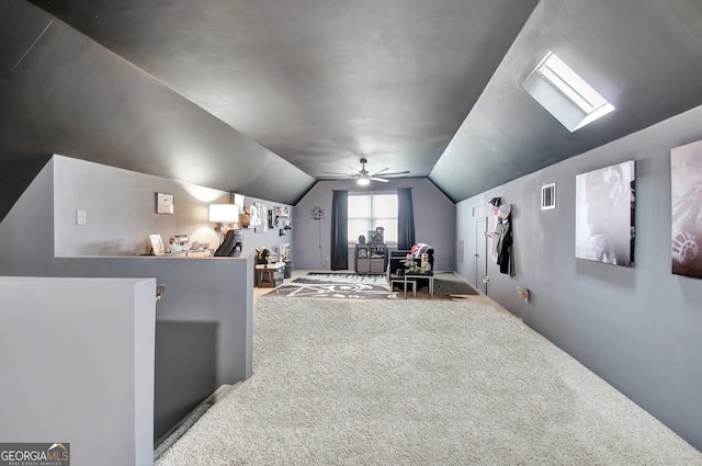 interior space featuring ceiling fan, lofted ceiling with skylight, and carpet flooring