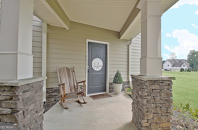 entrance to property featuring covered porch and a yard