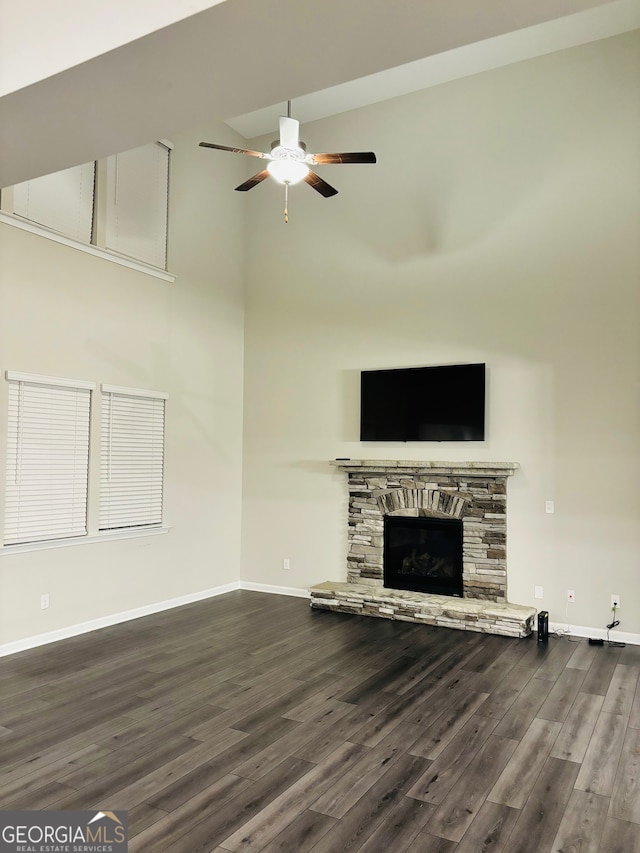 unfurnished living room with ceiling fan, a fireplace, and dark wood-type flooring