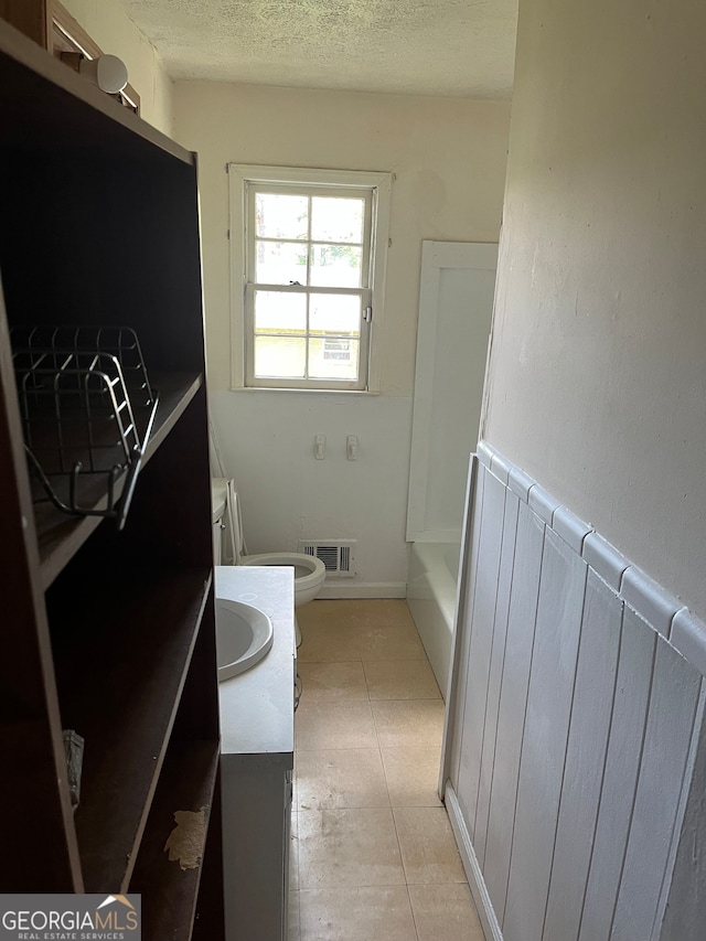 bathroom featuring tile patterned flooring, a textured ceiling, radiator heating unit, vanity, and toilet