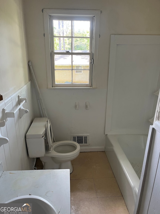 bathroom featuring tile patterned flooring, a bathing tub, and toilet