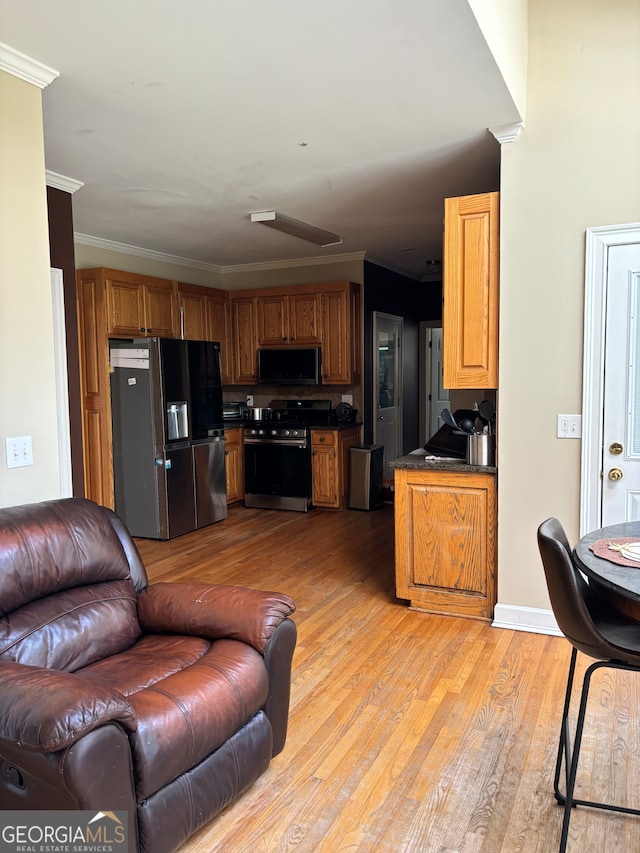 interior space featuring appliances with stainless steel finishes, light hardwood / wood-style flooring, and ornamental molding