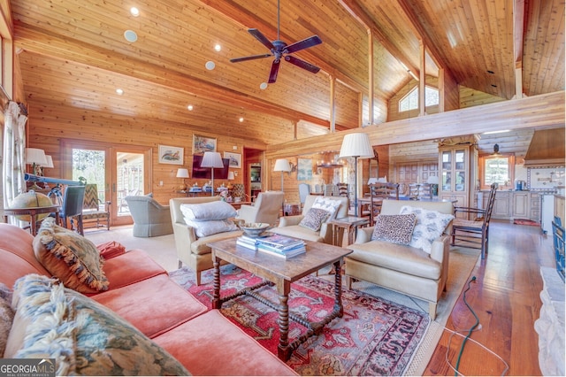 living room featuring wood-type flooring, wood walls, high vaulted ceiling, ceiling fan, and french doors