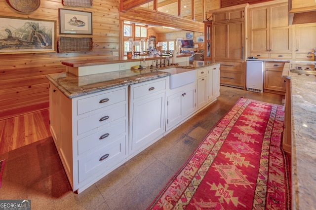 kitchen with a center island, wooden walls, sink, and white cabinetry