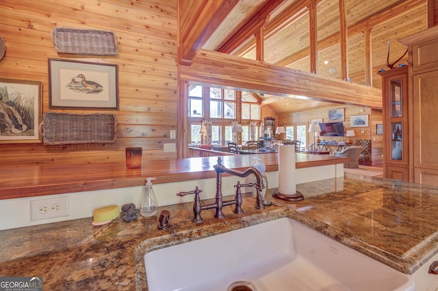 interior space featuring high vaulted ceiling, wooden walls, beamed ceiling, and sink