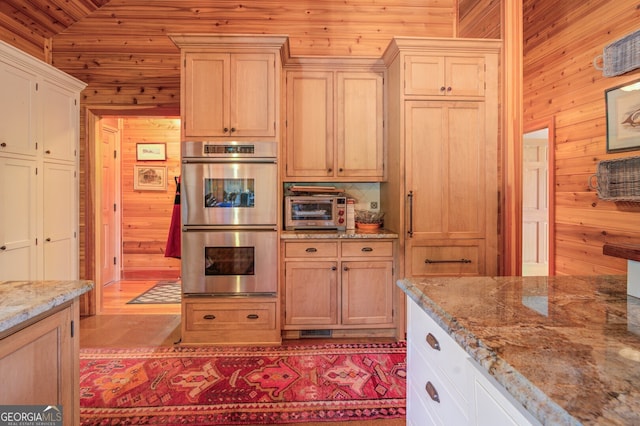 kitchen with light stone counters, wood walls, stainless steel double oven, decorative backsplash, and wooden ceiling