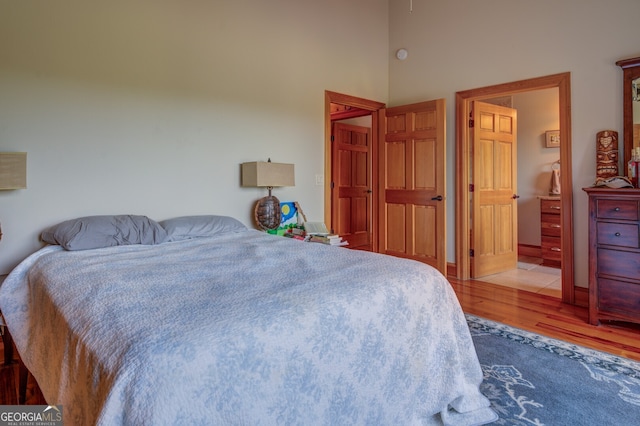 bedroom featuring light wood-type flooring and a high ceiling