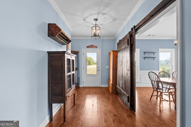 doorway to outside with ornamental molding, a notable chandelier, hardwood / wood-style floors, and a barn door