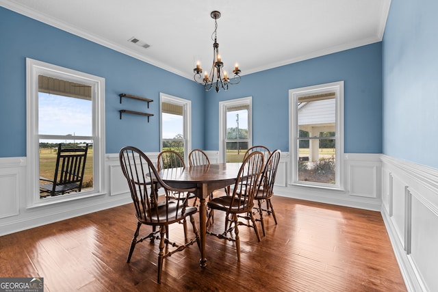 dining room with ornamental molding, plenty of natural light, dark wood-type flooring, and a chandelier