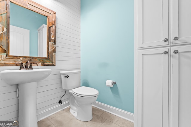 bathroom featuring sink, wooden walls, toilet, and tile patterned floors