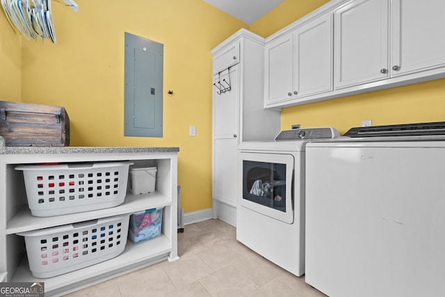 washroom with electric panel, independent washer and dryer, light tile patterned floors, and cabinets