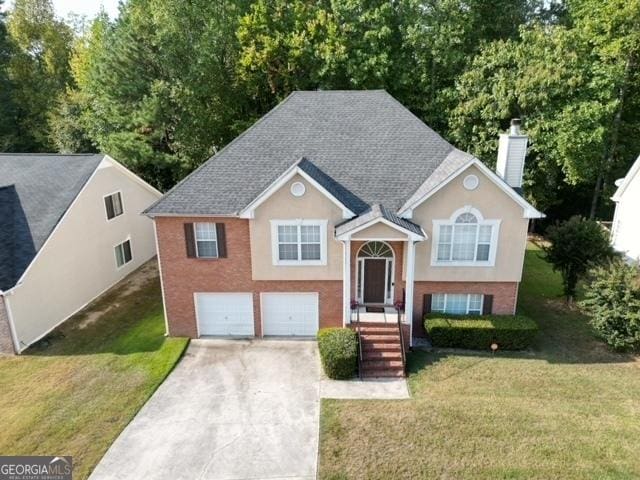 raised ranch featuring a garage and a front lawn