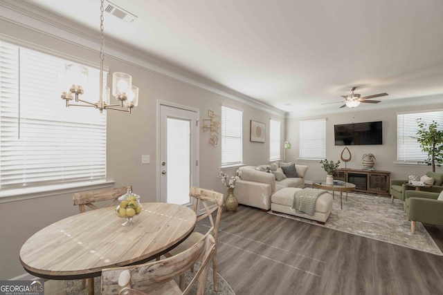 dining room with ceiling fan with notable chandelier, ornamental molding, and hardwood / wood-style floors