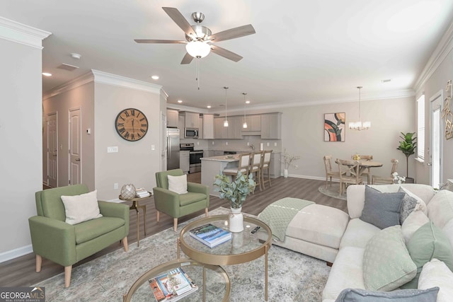 living room with wood-type flooring, ceiling fan with notable chandelier, and ornamental molding