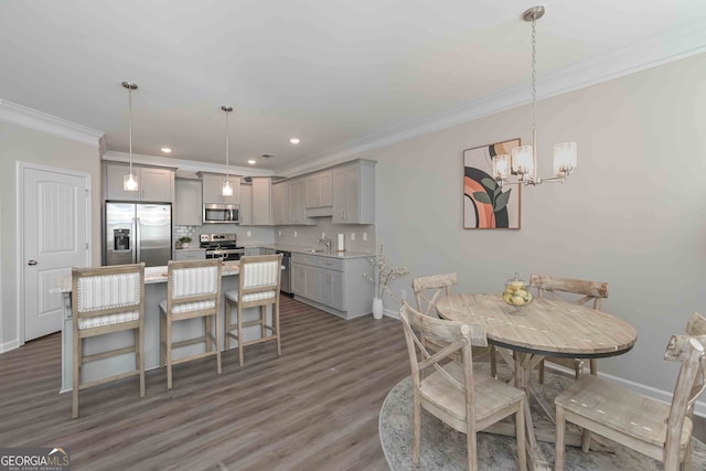 dining space featuring an inviting chandelier, dark hardwood / wood-style floors, sink, and crown molding