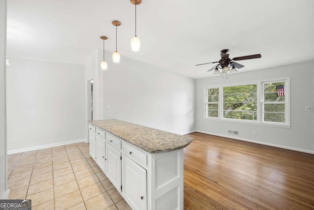 kitchen featuring light wood-type flooring, hanging light fixtures, ceiling fan, and white cabinets