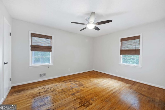 empty room with ceiling fan, plenty of natural light, and hardwood / wood-style floors